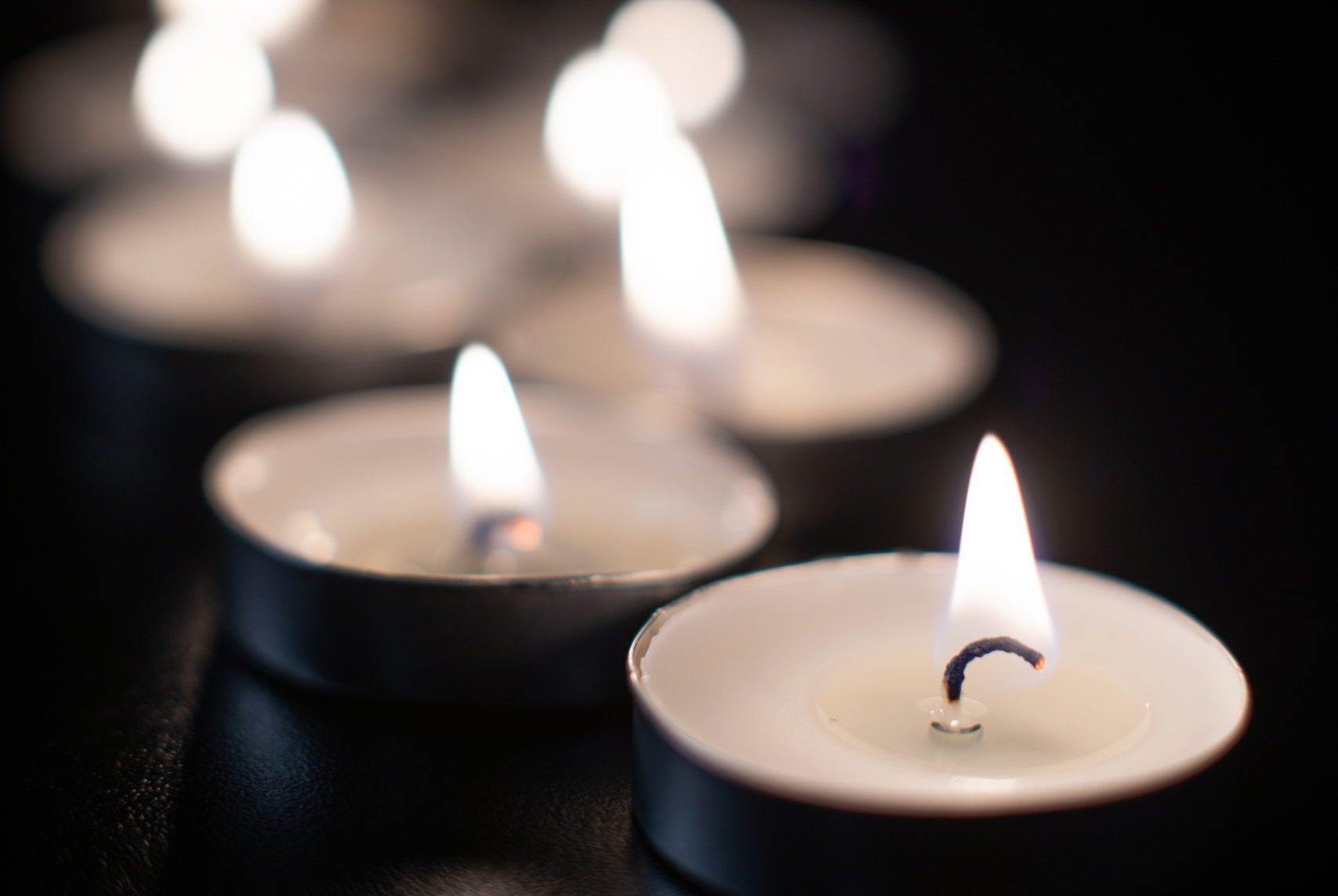 front view burning candles pitch black surface