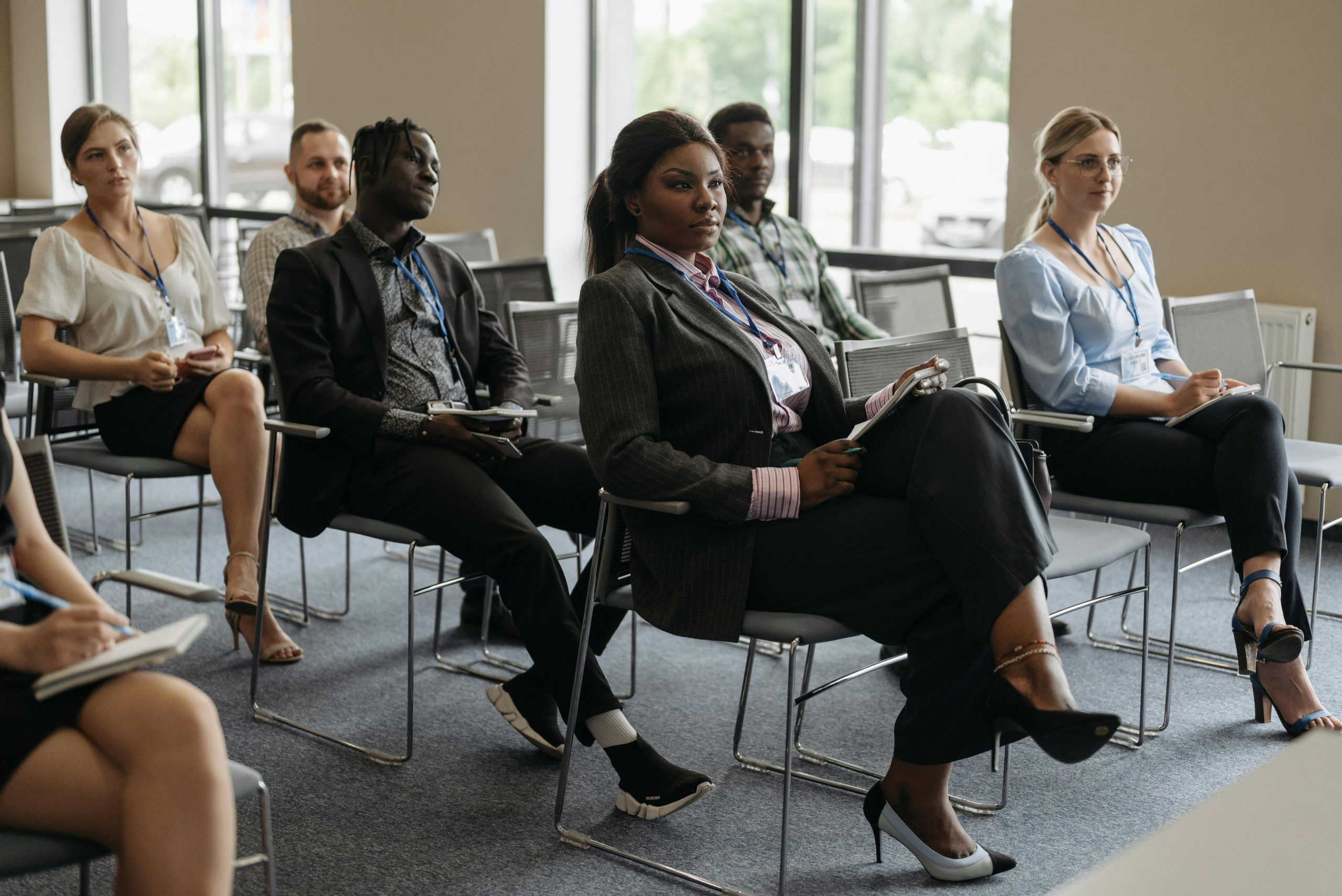 A diverse group of adults attentively listening at a business conference indoors.